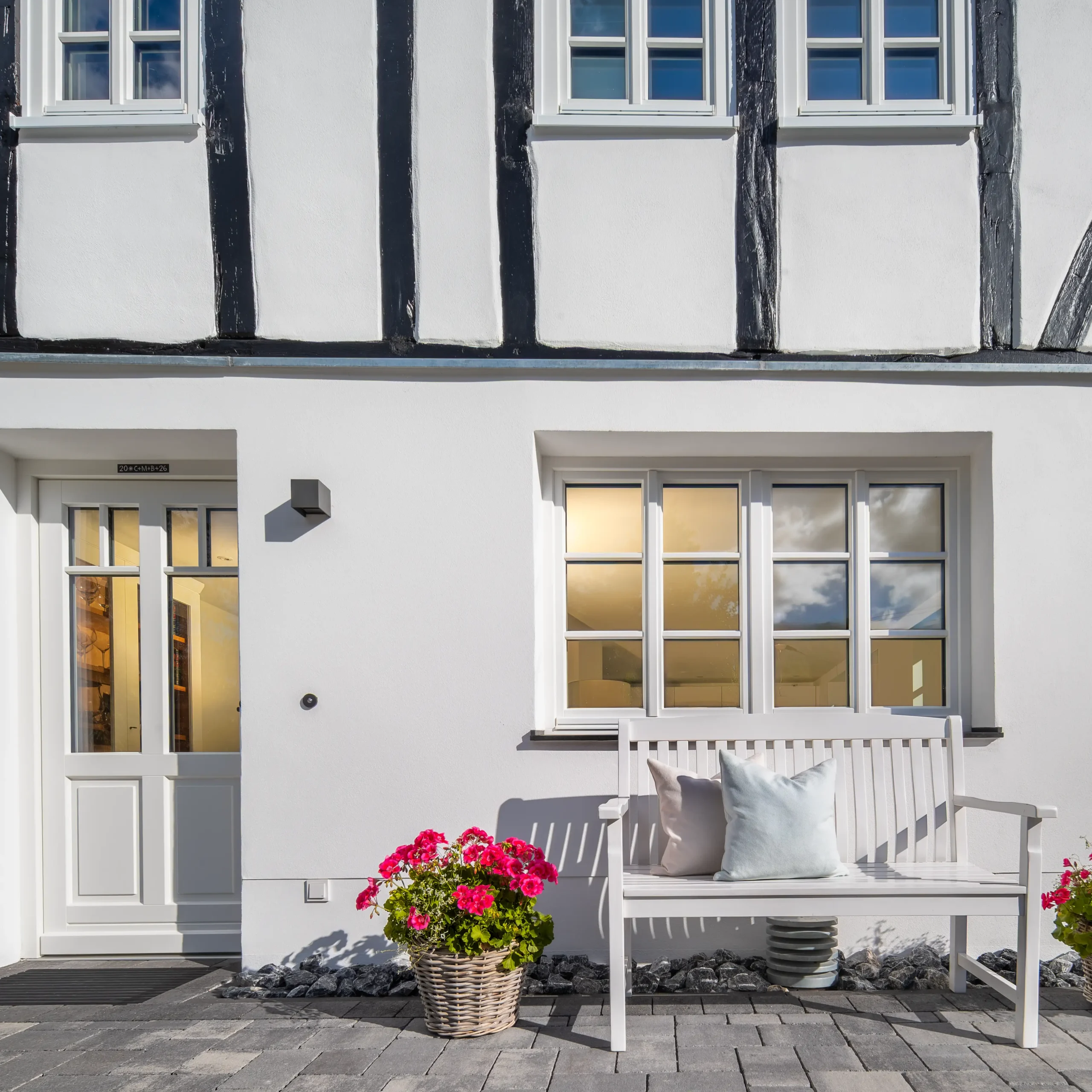 Eingang zur Ferienwohnung mit Gartenbank und Blumenkörben