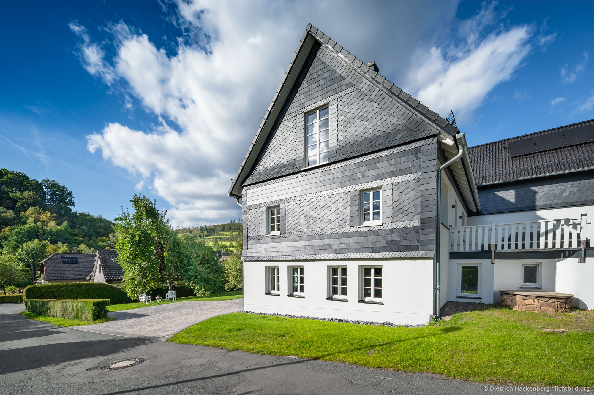 Seitenansicht der schieferbedeckten Fassade und Brunnen. Ferienwohnung in Eibens Fachwerkhaus, Kirchhundem-Benolpe, Sauerland