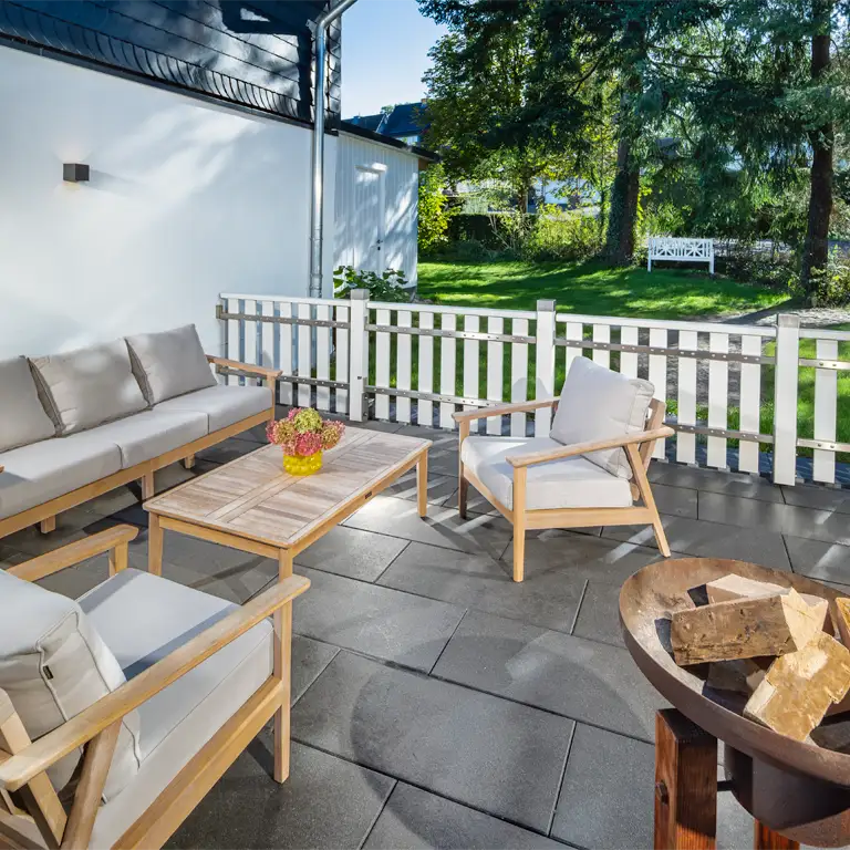Terrasse in der Morgensonne mit Lounge-Sitzgruppe und geschlossenem Zaunelement