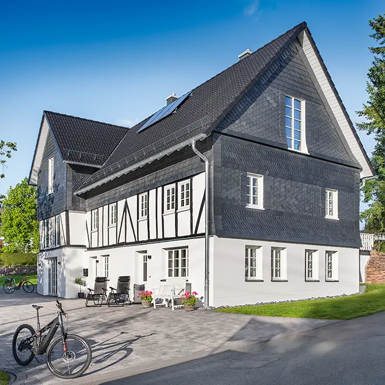 Fachwerkhaus mit parkenden Fahrädern und Eibenbusch. Ferienwohnung in Kirchhundem-Benolpe, Sauerland